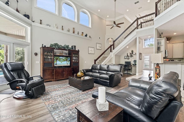 living room with a high ceiling, stairway, wood finished floors, and a wealth of natural light