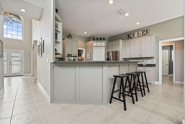 kitchen with stainless steel appliances, a peninsula, french doors, open shelves, and a kitchen bar