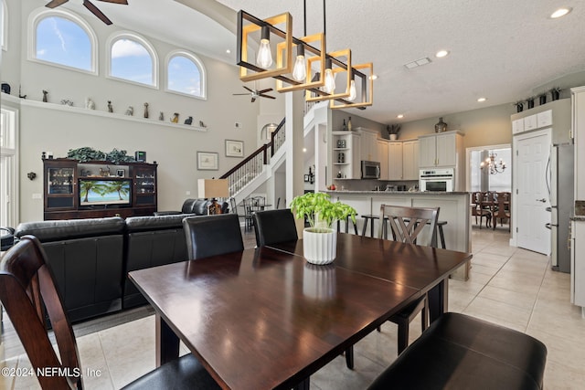 dining room featuring light tile patterned floors, stairway, a textured ceiling, and ceiling fan with notable chandelier