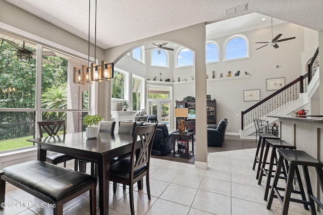 dining room with light tile patterned floors, stairway, ceiling fan with notable chandelier, and a wealth of natural light