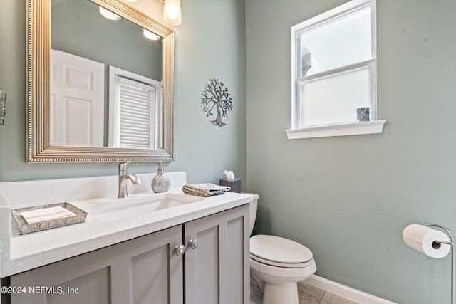 bathroom with tile patterned flooring, baseboards, vanity, and toilet