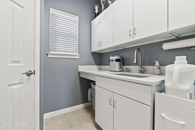 clothes washing area with light tile patterned floors, a sink, and baseboards