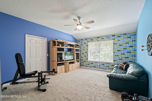 interior space with lofted ceiling, ceiling fan, a textured ceiling, and carpet