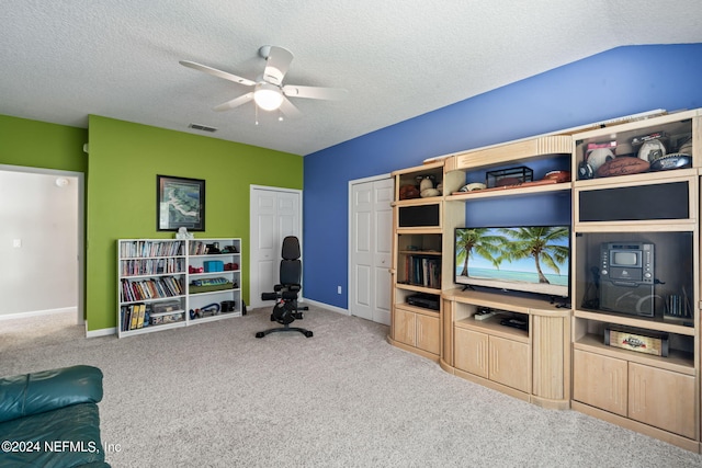 office space featuring a textured ceiling, carpet flooring, visible vents, baseboards, and a ceiling fan