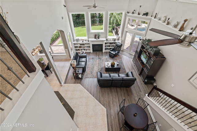 living room with stairs, a high ceiling, a fireplace, and a ceiling fan