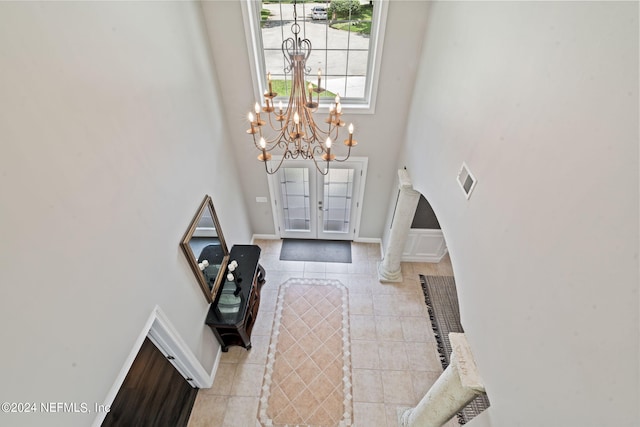 tiled foyer with visible vents, a high ceiling, baseboards, and french doors