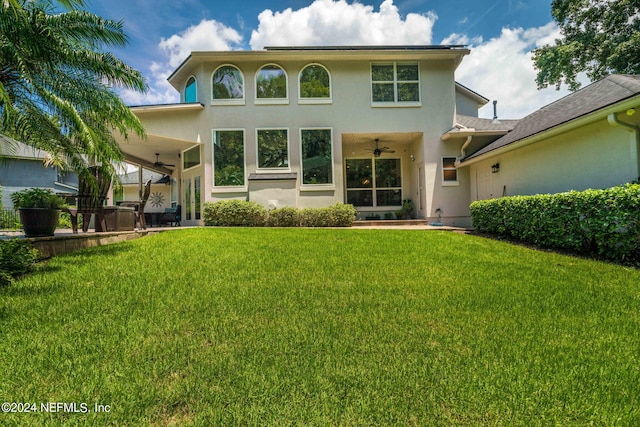 rear view of property featuring a yard and stucco siding