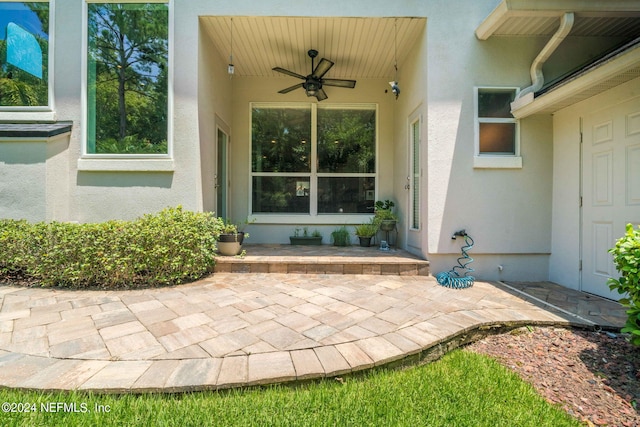 entrance to property with a patio, a ceiling fan, and stucco siding