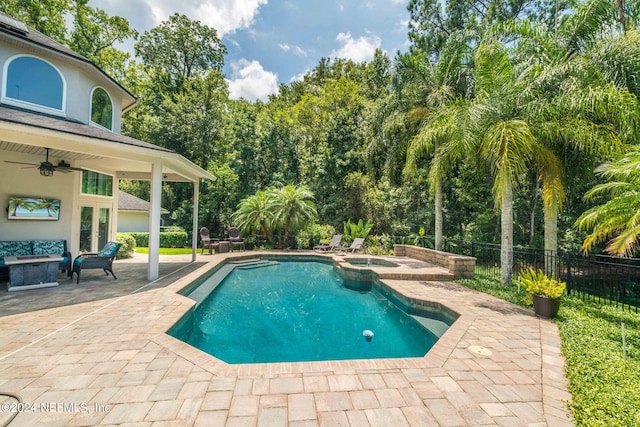 view of pool featuring a patio, an outdoor fire pit, fence, a pool with connected hot tub, and a ceiling fan