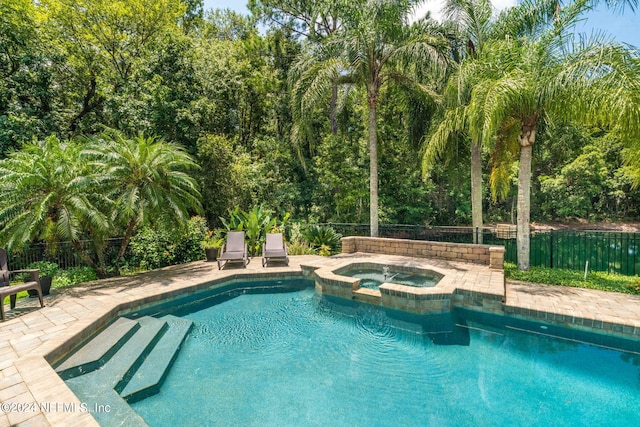 view of pool with a pool with connected hot tub, a patio area, and fence