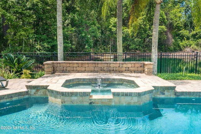 view of pool with a pool with connected hot tub and fence