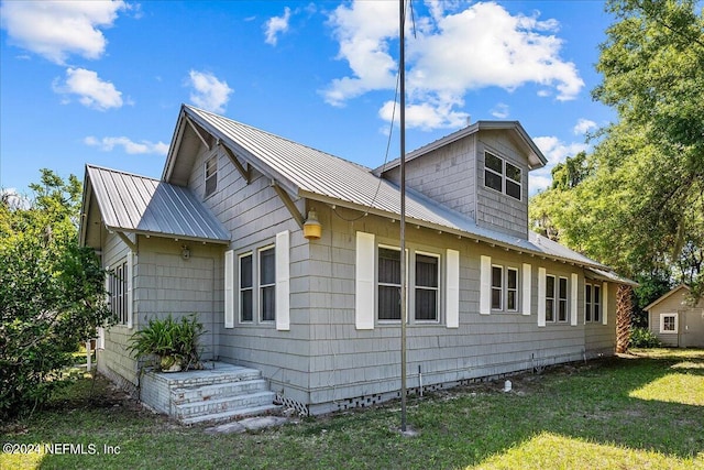 view of side of home with metal roof and a yard