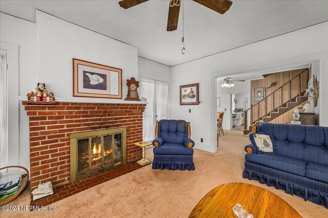 carpeted living room with stairs, a fireplace, and ceiling fan