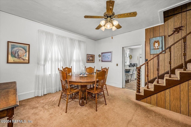 dining room featuring a ceiling fan, carpet flooring, baseboards, and stairs