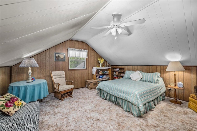 carpeted bedroom with vaulted ceiling, ceiling fan, and wooden walls