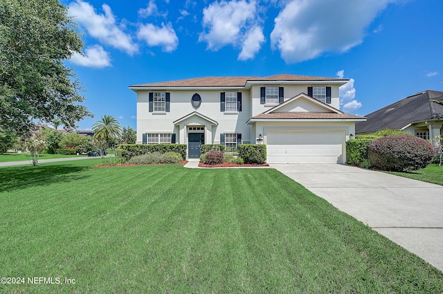 view of front of property with an attached garage, stucco siding, concrete driveway, and a front yard