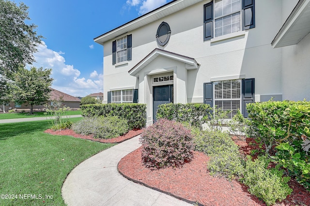 property entrance featuring a lawn and stucco siding