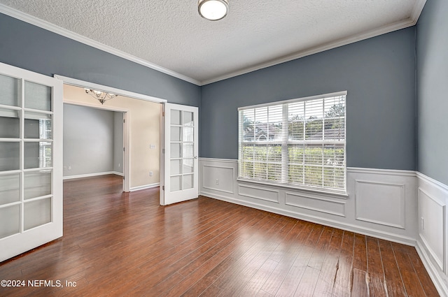 empty room with crown molding, wood-type flooring, a textured ceiling, and french doors