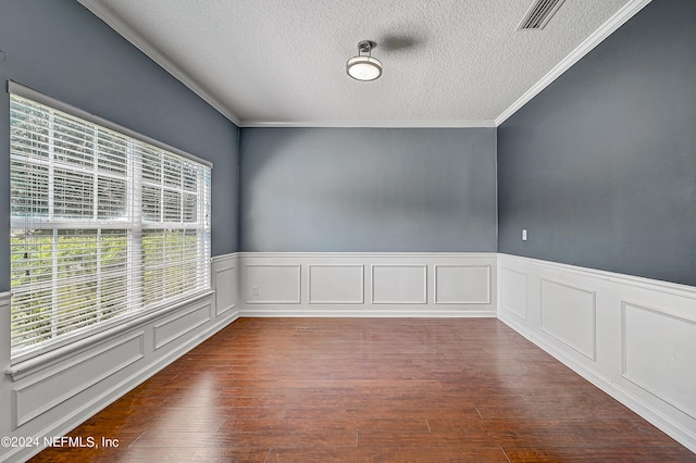 spare room with a textured ceiling, ornamental molding, wood finished floors, and visible vents