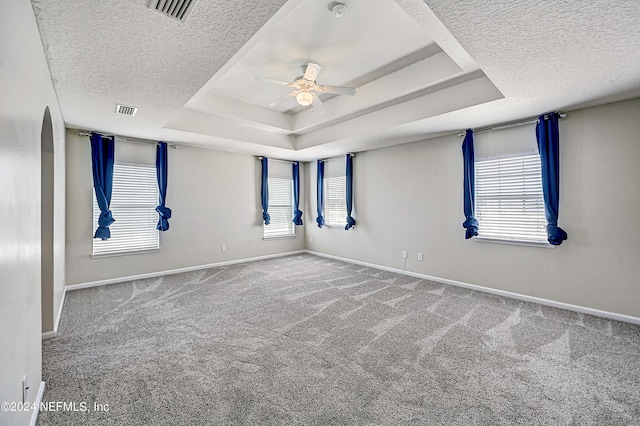 unfurnished room with a tray ceiling, carpet, and visible vents