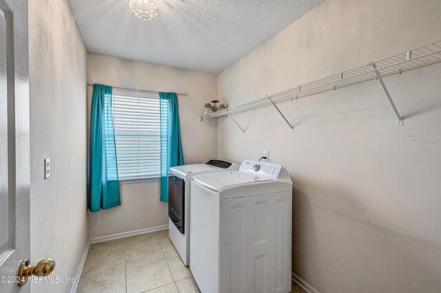 clothes washing area with light tile patterned floors, a textured ceiling, and washer and dryer