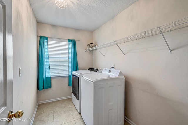 laundry room featuring light tile patterned floors, a textured ceiling, laundry area, baseboards, and washer and clothes dryer