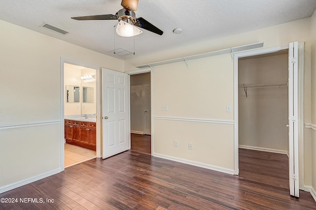 unfurnished bedroom featuring a closet, dark wood-style flooring, visible vents, and a textured ceiling