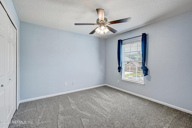 unfurnished bedroom featuring ceiling fan, a textured ceiling, carpet floors, and a closet