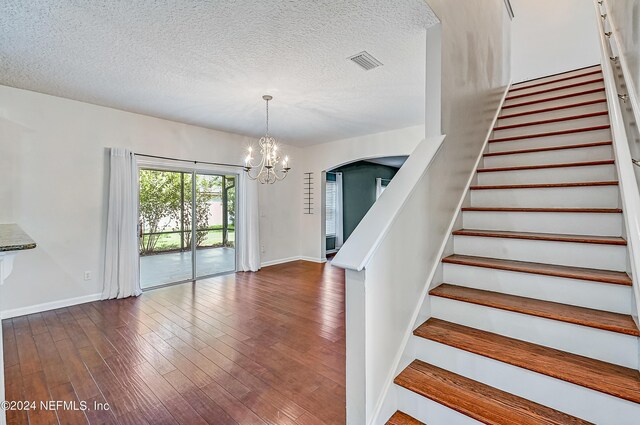 stairs featuring a notable chandelier, a textured ceiling, and hardwood / wood-style floors