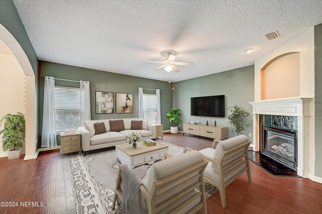 living room featuring hardwood / wood-style floors, a fireplace, a textured ceiling, and ceiling fan