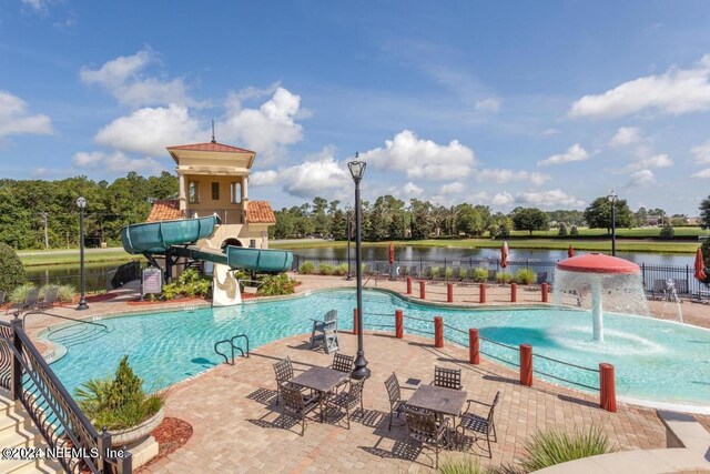 view of swimming pool featuring a water slide, a patio, and a water view