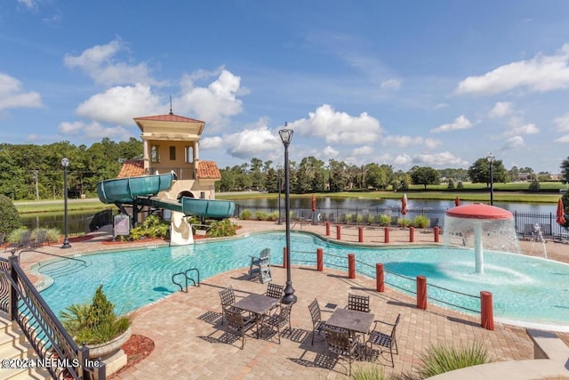 community pool featuring a water slide, a patio area, fence, and a water view