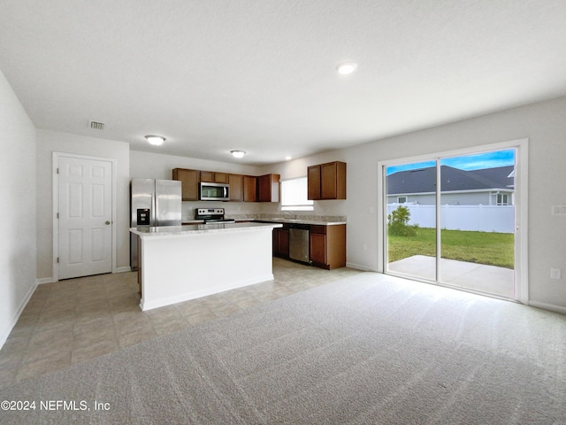 kitchen with stainless steel appliances, a kitchen island, and light carpet