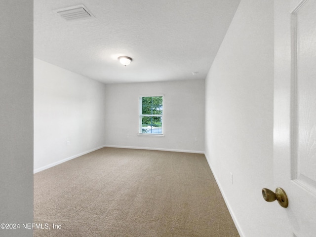 carpeted empty room featuring a textured ceiling