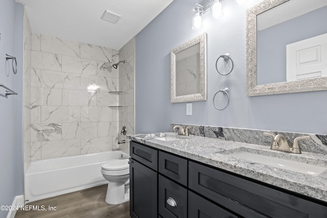 full bathroom with hardwood / wood-style flooring, tiled shower / bath, vanity, and toilet