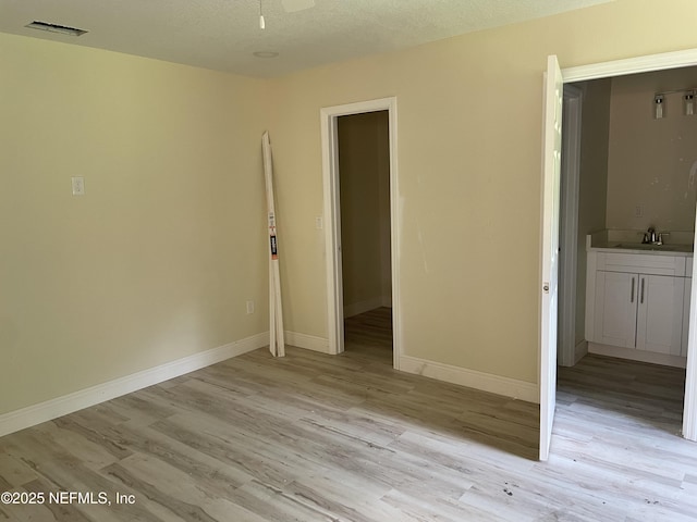 1058 W 17th St, Jacksonville, FL 32209 - unfurnished bedroom featuring baseboards, a sink, light wood-style flooring, and visible vents