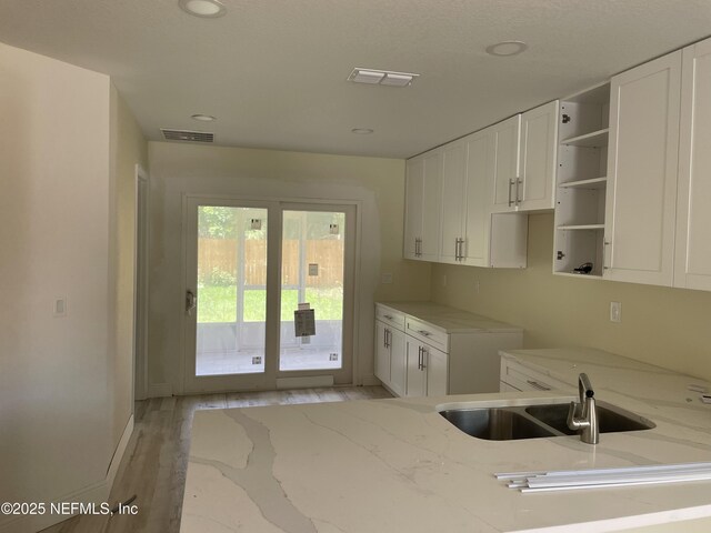 1058 W 17th St, Jacksonville, FL 32209 - kitchen featuring a sink, light stone countertops, white cabinetry, and visible vents