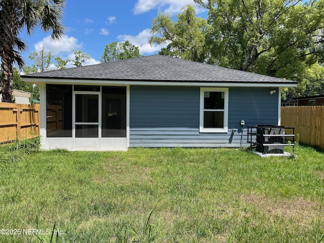 1058 W 17th St, Jacksonville, FL 32209 - rear view of house with fence, a lawn, a shingled roof, and a sunroom