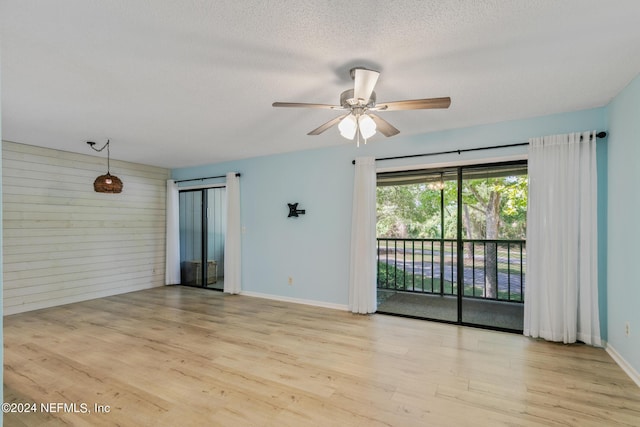 unfurnished room with ceiling fan, wooden walls, wood finished floors, and a textured ceiling