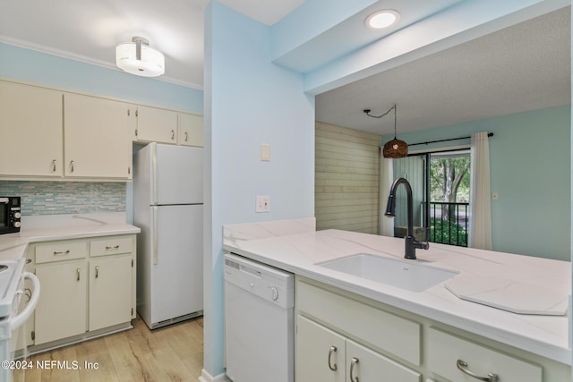 kitchen featuring white appliances, light stone countertops, a sink, light wood-style floors, and tasteful backsplash