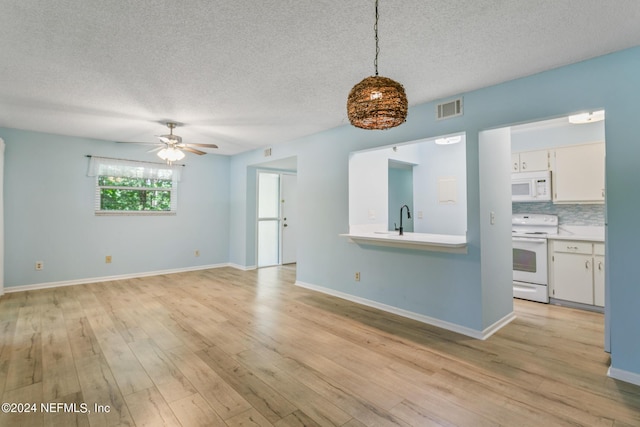 interior space with visible vents, baseboards, a textured ceiling, and light wood-style flooring