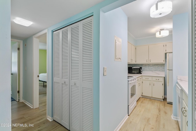 kitchen with light wood finished floors, baseboards, light countertops, decorative backsplash, and white appliances