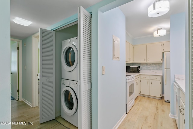 clothes washing area with laundry area, stacked washer and dryer, crown molding, and light wood finished floors