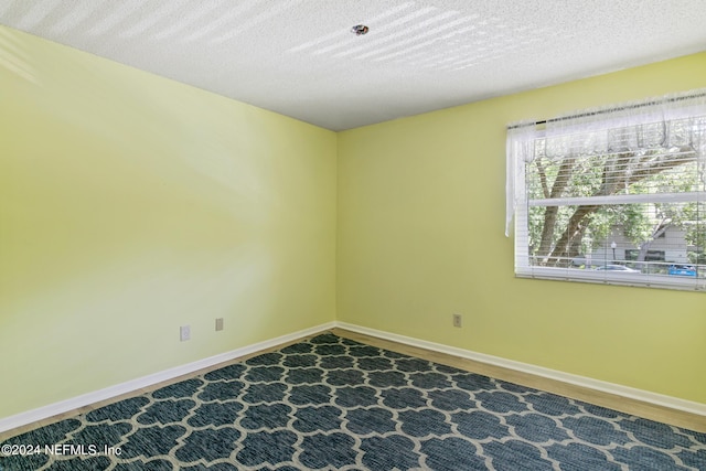 empty room featuring wood finished floors, baseboards, and a textured ceiling