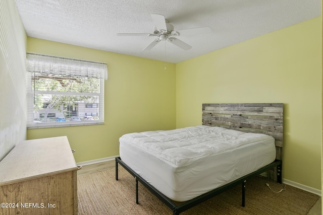 bedroom with wood finished floors, baseboards, a textured ceiling, and ceiling fan