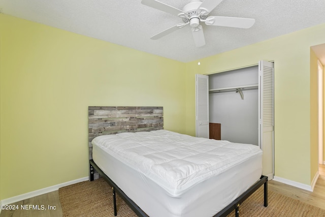 bedroom with wood finished floors, a closet, and baseboards