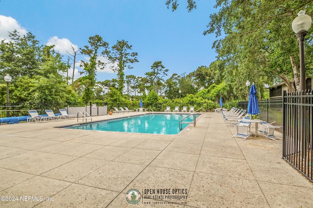 community pool with a patio area and fence