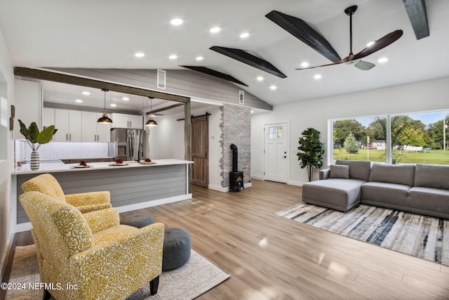 living room with a barn door, ceiling fan, light hardwood / wood-style floors, lofted ceiling with beams, and brick wall