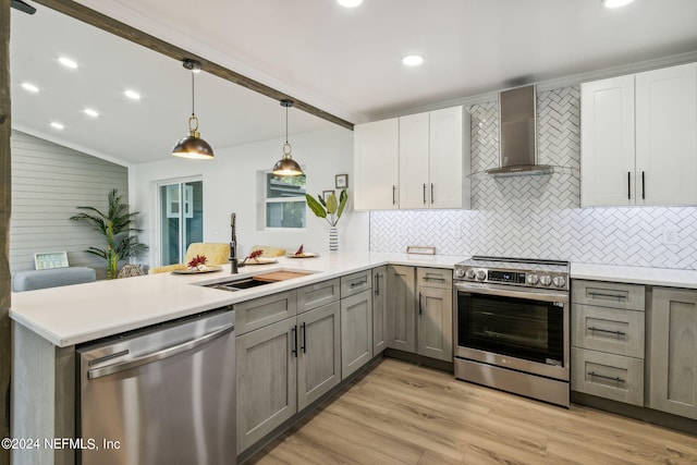 kitchen with gray cabinetry, light hardwood / wood-style flooring, appliances with stainless steel finishes, and wall chimney exhaust hood