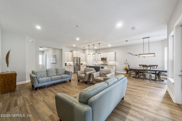 living room featuring light hardwood / wood-style floors, sink, and a textured ceiling